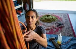 Rope Safety Mastered: Inspect, Care, Retire Guide A climber embodying rope safety by inspecting a rope, with care items nearby and a retired rope repurposed as a mat, covering the full inspect, care, and retire guide.