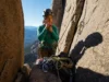 Simple Partner Rescue: For Stuck or Injured Climbers A female climber at a belay station on a multi-pitch route, assessing her gear to perform a simple partner rescue for a stuck or injured climber.
