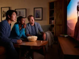 Diverse group of friends watching an inspiring climbing film on a large screen, faces lit with awe, for the ultimate guide to climbing films and docs.