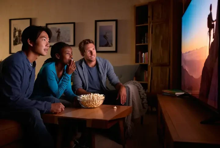 Diverse group of friends watching an inspiring climbing film on a large screen, faces lit with awe, for the ultimate guide to climbing films and docs.