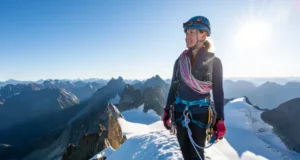 Unlock Alpine Success: Fundamental Skills Guide Alpinist on a snowy summit with ice axe and rope, overlooking mountain vista, having unlocked alpine success through fundamental climbing skills.