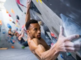 Boulderer executing a powerful move on an indoor wall, showcasing bouldering power, strong finger grip, and a solid lock-off, for a guide on building these strengths.