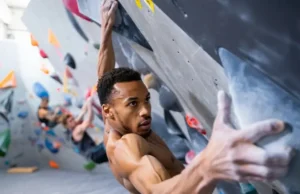 Build Bouldering Power, Finger & Lock-off Strength Boulderer executing a powerful move on an indoor wall, showcasing bouldering power, strong finger grip, and a solid lock-off, for a guide on building these strengths.