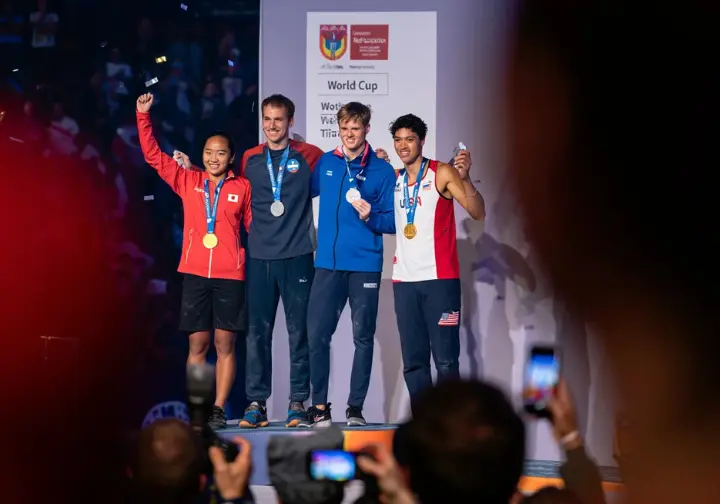Three diverse climbers on the podium at an IFSC World Cup, smiling with their medals, illustrating the foundational structure of the international circuit.
