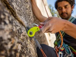 Close-up of a climber's hands skillfully placing a camming device into a granite crack, illustrating the art and introduction to placing trad climbing protection.
