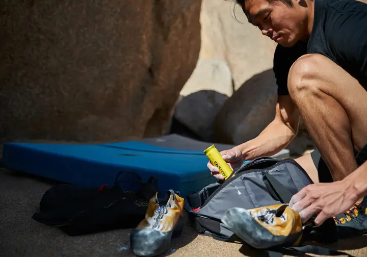 A climber puts deodorizing inserts into his climbing shoes and clips them to his bag to air out, illustrating how to prevent and eliminate shoe odor.