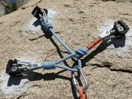 Perfectly constructed bombproof trad climbing anchor on granite, showcasing SERENE/ERNEST principles with cams, nuts, and an equalized cordelette master point.