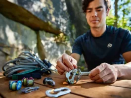 Climber organizing essential trad rack components (nuts, cams, alpine draws, nut tool) at a granite crag, prioritizing gear for building their first trad rack.