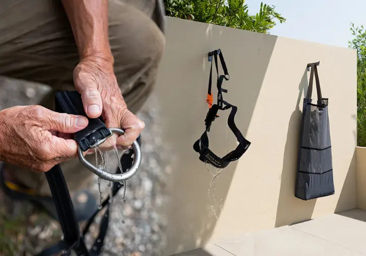A visual guide showing the three stages of climbing harness care: hands inspecting the belay loop, the harness air-drying, and a storage bag ready.