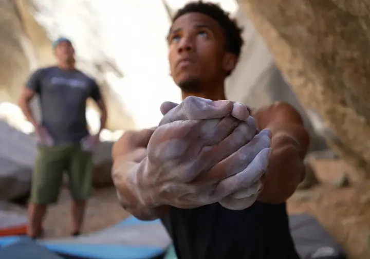 Close-up of a bouldering spotter's hands in correct "spoons" position, alert and ready to guide a fall, demonstrating mastering spotting techniques for effective bouldering safety.