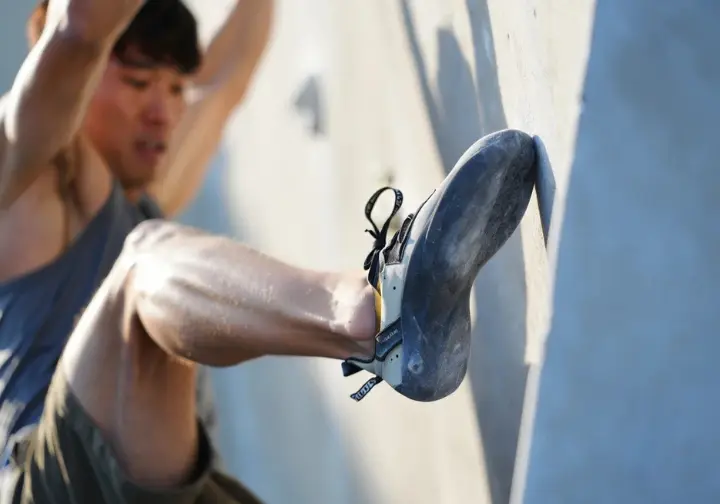 Detailed close-up of a climber executing a perfect heel hook, showcasing fundamental mechanics, body positioning, and muscle engagement for understanding advanced bouldering moves.