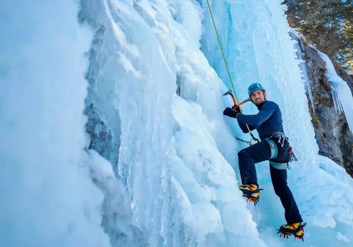 Ice climber ascending a stunning frozen waterfall with varied ice textures, illustrating the challenging and beautiful frozen frontier of understanding ice climbing.