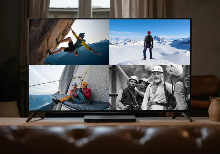 A TV screen displaying a grid of climbing film thumbnails showcasing diverse disciplines like bouldering, alpine, big wall, and historical climbing.