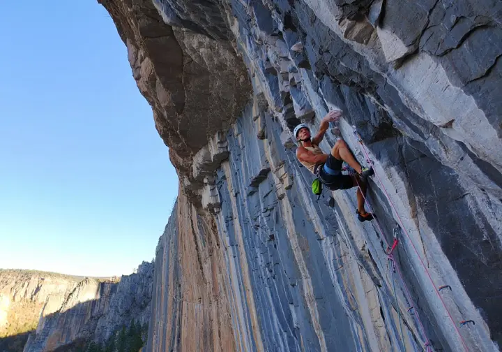 Sport climber on a long, impressive limestone route with tufas in Mexico or the US Mountain West, showcasing legendary sport climbing destinations.