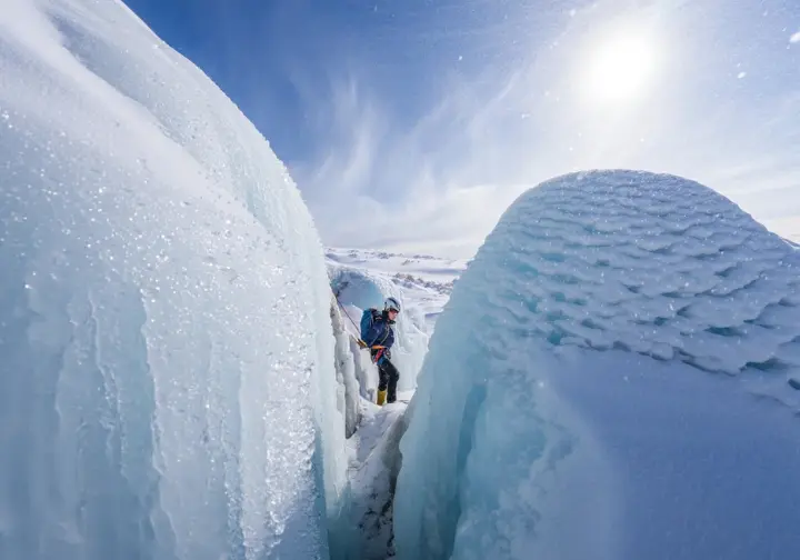 Frozen waterfall showing contrasting ice conditions: one side sunlit and wet, the other shaded and frosty, illustrating weather's dynamic role and how meteorological factors shape ice.