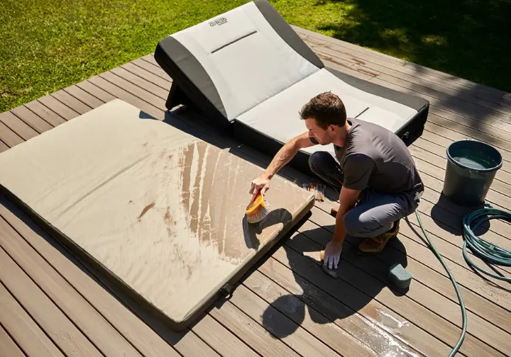 Climber cleaning and airing out a bouldering crash pad outdoors, demonstrating proper care and maintenance for extending its lifespan.