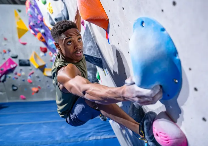 Boulderer skillfully executing a core bouldering technique like a heel hook or dyno on an indoor climbing wall, mastering essential bouldering movements.