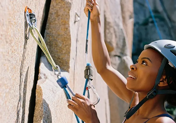 Trad climber demonstrating strategic sling usage by either extending a placement with an alpine draw to reduce rope drag or equalizing two pieces of protection at an anchor.