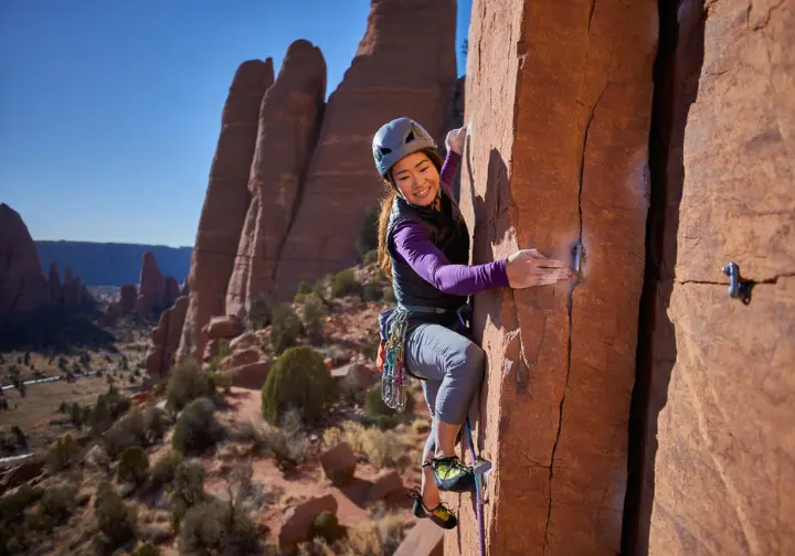 Climber on a unique rock type (e.g., volcanic tuff, conglomerate cobbles, or pocketed dolomite) in a scenic high-altitude sport climbing haven.