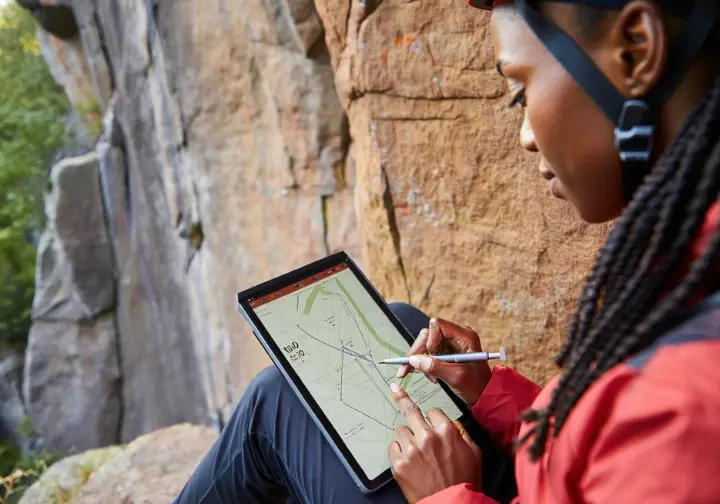Experienced climber intently studying a detailed climbing topo map at an outdoor crag, with the actual sport route visible, honing advanced route reading prowess.