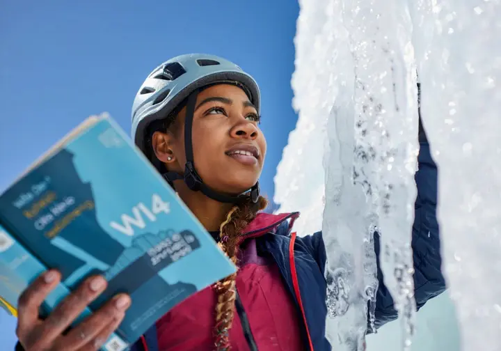 Ice climber comparing a guidebook grade (e.g., WI4) with the actual variable conditions of a frozen waterfall, interpreting difficulty and risk beyond the nominal grade.
