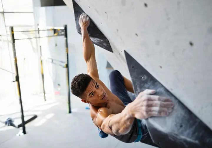 Strong boulderer holding a perfect one-arm lock-off at a 90-degree angle on a steep wall or bar, showcasing training for static bouldering supremacy and lock-off strength.