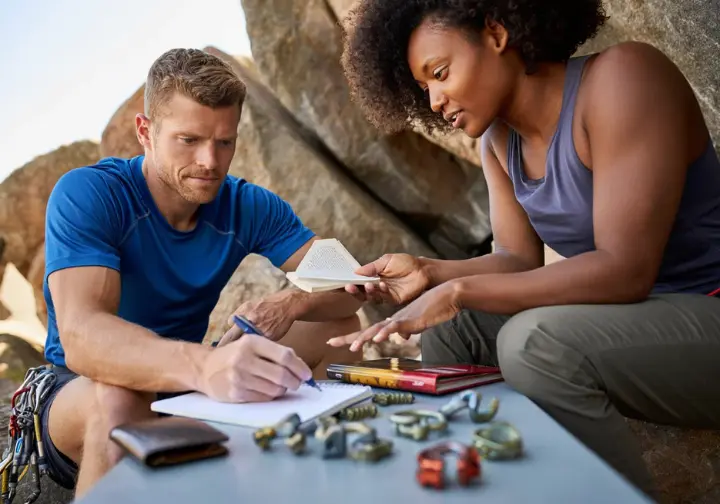 Experienced climber mentoring a newer climber on strategically and economically prioritizing purchases for building their first trad rack, with starter gear displayed.