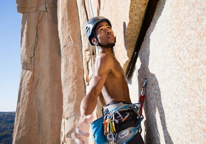 Trad climber leading a granite crack route, focused on placing protection and assessing the next moves, embodying the process of taking the sharp end.