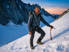7 Alpine Climbing Skills That Actually Keep You Safe Alpine climber in cane position on steep snow slope holding Petzl ice axe, mountains at dawn