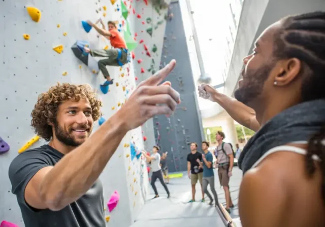 Diverse climbers ascend a massive, modern artificial climbing wall, symbolizing the challenge and scale of the largest climbing walls in the world.