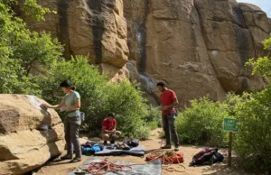 The Climber’s Guide to Leave No Trace Ethics (LNT) Diverse climbers practicing Leave No Trace ethics at a pristine crag, including brushing holds and using a rope tarp, for a guide to LNT.