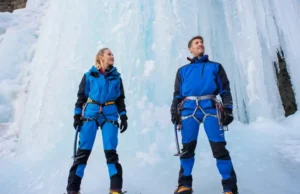 The Complete Ice Climbing Gear System Explained Two ice climbers with a complete gear system standing before a large frozen waterfall, ready for a climb.