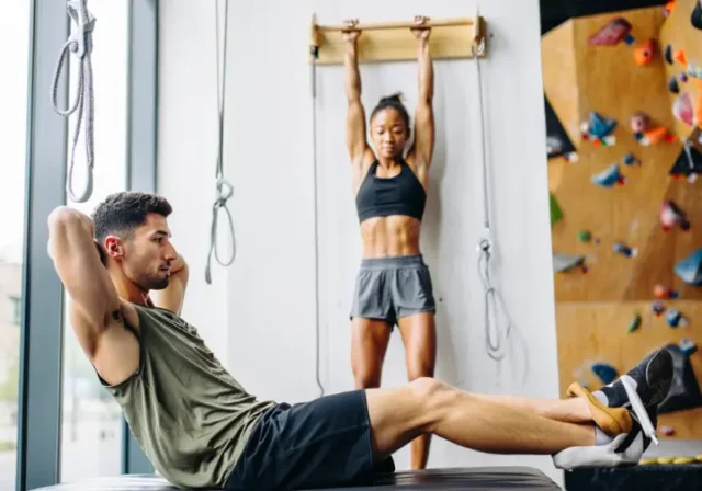 Diverse climbers performing core and grip exercises in a modern gym, illustrating a comprehensive gym workout plan for climbers.