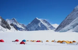Beyond the Icefall: A Look at Everest’s Camp 1 Photorealistic image of Mount Everest's Camp 1, showing colorful tents nestled in a snow-covered basin surrounded by towering peaks under a clear sky, highlighting its strategic location.