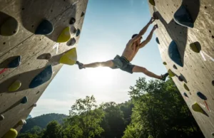 High Protein High Fat Low Carb Diet for Peak Power A male rock climber mid-air, performing an explosive dyno on an outdoor rock wall, showcasing peak power with a high protein high fat low carb diet.