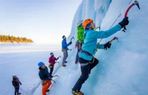 Midwest Ice: A Guide to Climbing in Michigan’s U.P. Diverse ice climbers ascend a towering blue and white ice formation above Lake Superior in Michigan's U.P., demonstrating the region's prime ice climbing.