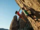 Smart Rock Climbing Training Program: Get Stronger Two climbers, male and female, ascending a steep rock face under clear skies, demonstrating strength and smart rock climbing training.