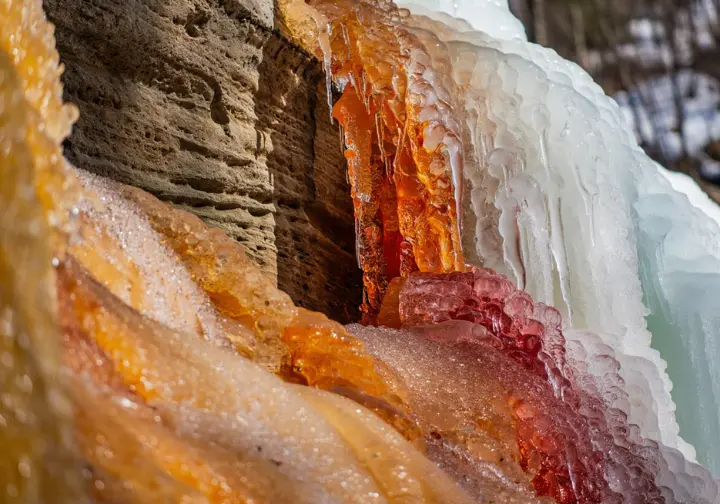 Close-up of colorful ice formations on porous sandstone cliffs in Michigan's U.P., showcasing the unique geology and character of the ice climbing.