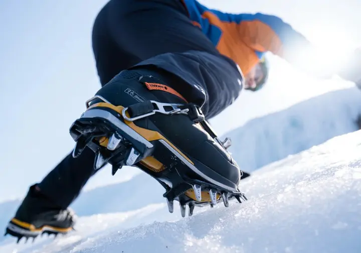 Close-up of a mountaineering boot and crampon firmly connected to ice, highlighting the foundation system of ice climbing gear.