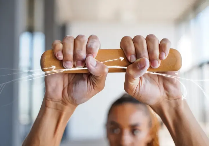 Close-up of climber's hands on a hangboard with subtle scientific graphics, representing the scientific foundation of a gym workout for climbers.