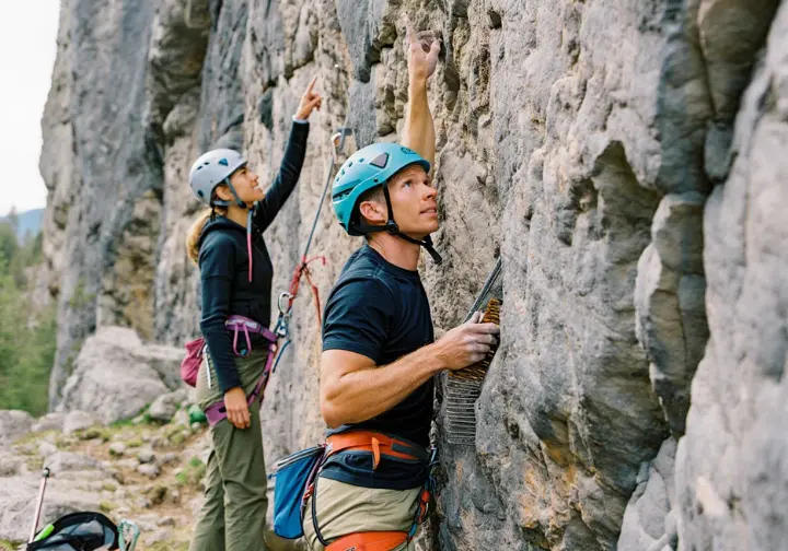 Rock climbing route developers cleaning and envisioning a new route, demonstrating the craft from vision to reality in first ascent climbing.