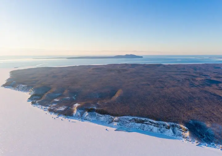 Panoramic aerial view of Michigan's U.P. winter landscape, highlighting diverse ice climbing regions like an atlas, for ice climbing in Michigan.
