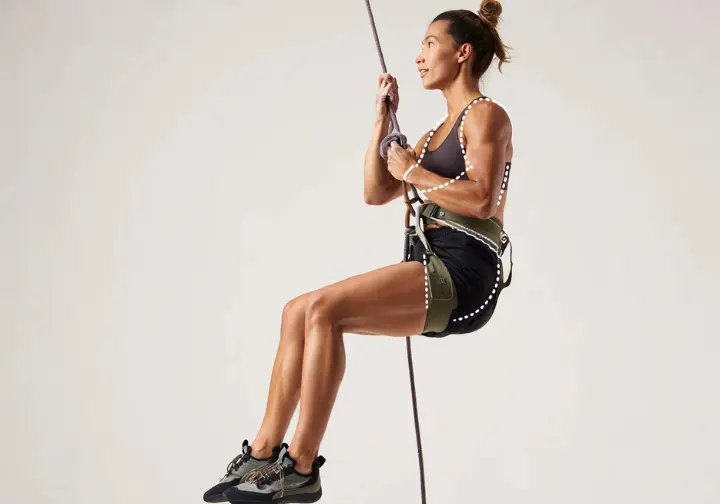 Side profile of a female climber wearing a properly fitted women's rock climbing harness, illustrating the non-negotiable importance of women's specific fit.
