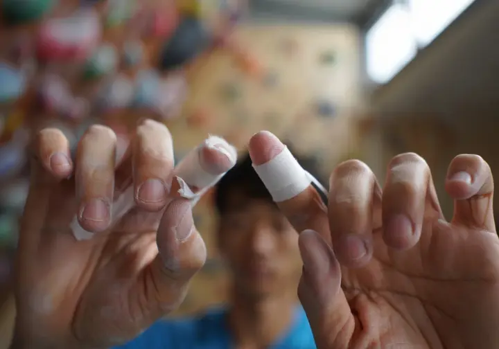 Close-up of climber's hands demonstrating proper rock climbing finger tape application, highlighting best practices and avoiding common mistakes.