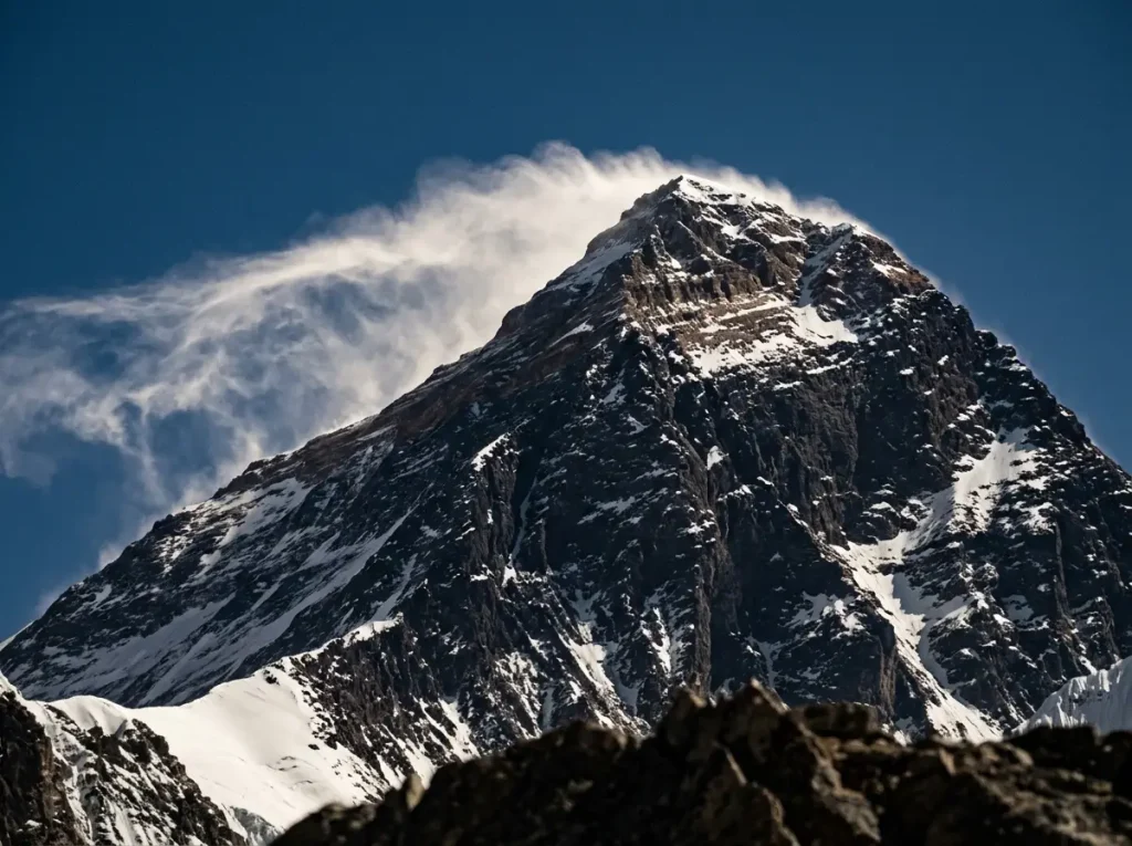 Wind-blown snow plume streaming off the rocky summit pyramid of Mount Everest