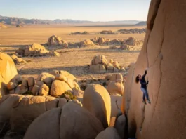 A climber on a massive granite boulder in a stunning valley, representing the best bouldering in the world for all levels.