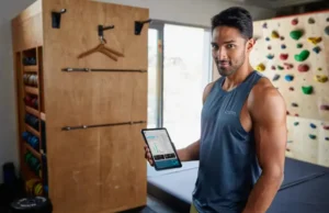 Climbing Assessment: A Data-Backed Framework to Find & Fix A dedicated climber analyzes performance data on a tablet in their home training area, demonstrating a data-backed framework to assess and fix climbing weaknesses.