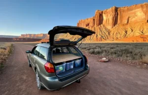 The Climber’s Blueprint to Finding Free & Cheap Camping A climber's car is set up for cheap camping in a free, dispersed spot with a view of a massive desert rock climbing cliff at sunrise.