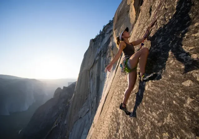 A climber demonstrates masterful footwork on a massive granite wall, embodying the science and art of an edging and smearing masterclass.