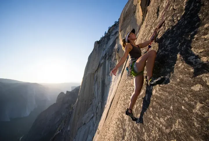 A climber demonstrates masterful footwork on a massive granite wall, embodying the science and art of an edging and smearing masterclass.